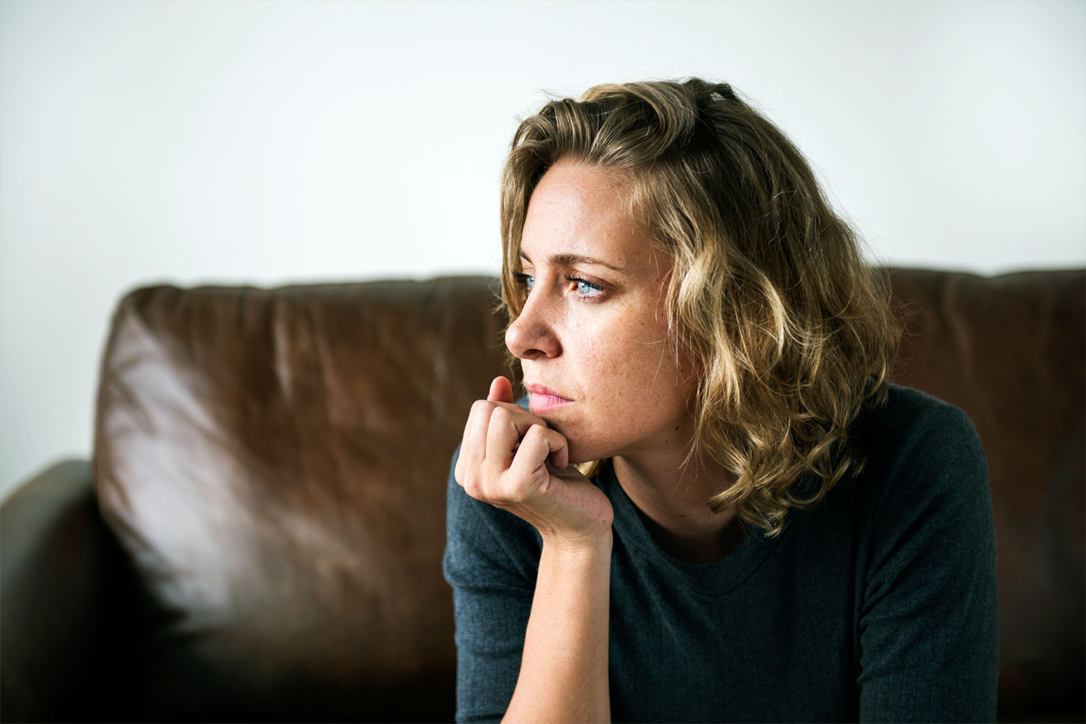 Nachdenkliche Frau sitzt ruhig auf einem Sofa